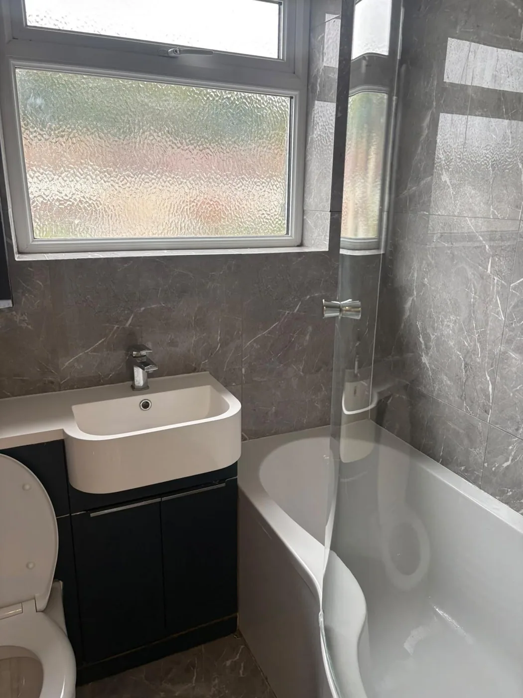 Separate bathroom with a clean bath and shower screen
